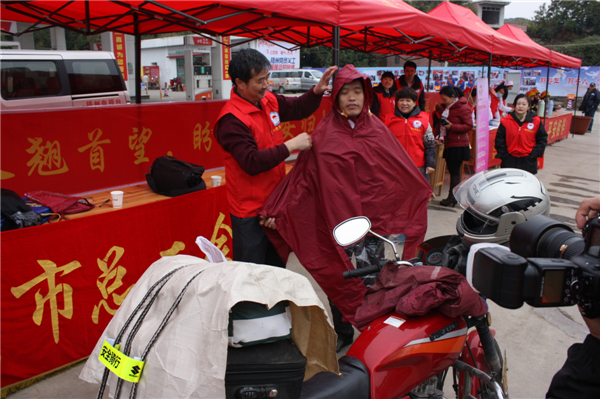 梧州市總工會的黨員義工們在市東出口春運服務(wù)站助力&ldquo;摩托大軍&rdquo;平安返鄉(xiāng)，幫助他們檢查車輛和行李，穿上雨衣。--黃賀峰攝.j